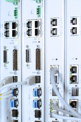 Close-up of networking hardware and server ports with various cabling connected, showing indicator lights and connectors used for data transmission in a server room or data center.